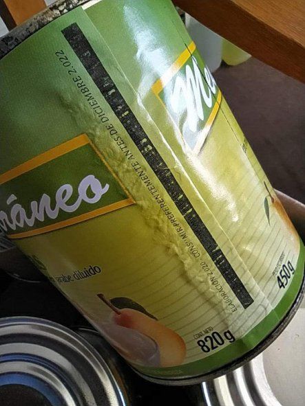 Primer plano de la fecha tachada burdamente y vuelta a escribir en las latas de pera en Azul.