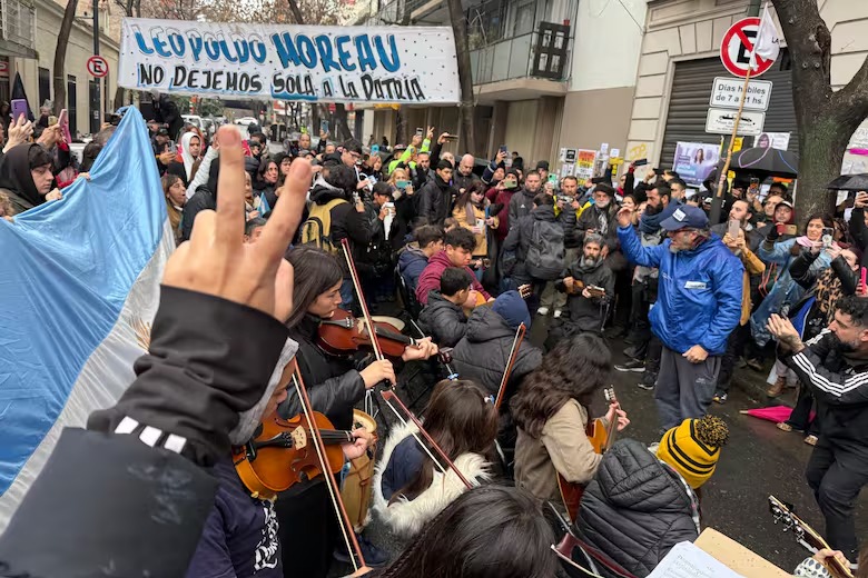 La orquesta de niños de Quilmes toca en la vigilia en la casa de CFK en Constitución, rodeados de miitancia peronista, bandera argentina y pasacalles.