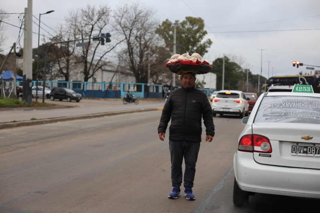 Vendedor ambulante con gorro y ropa de abrigo en una avenida de La Plata durante una mañana fría y nublada.