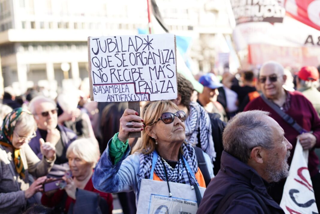 Mujer sostiene cartel durante marcha de jubilados frente al Congreso en la previa al Día de la Ancianidad