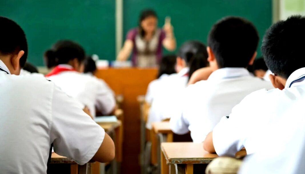 Alumnos en un aula escolar con la docente al frente de la clase.