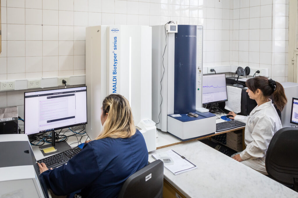 Dos científicas trabajan con el equipo MALDI Biotyper Sirius en el Instituto Malbrán, utilizando inteligencia artificial para diagnóstico microbiológico.