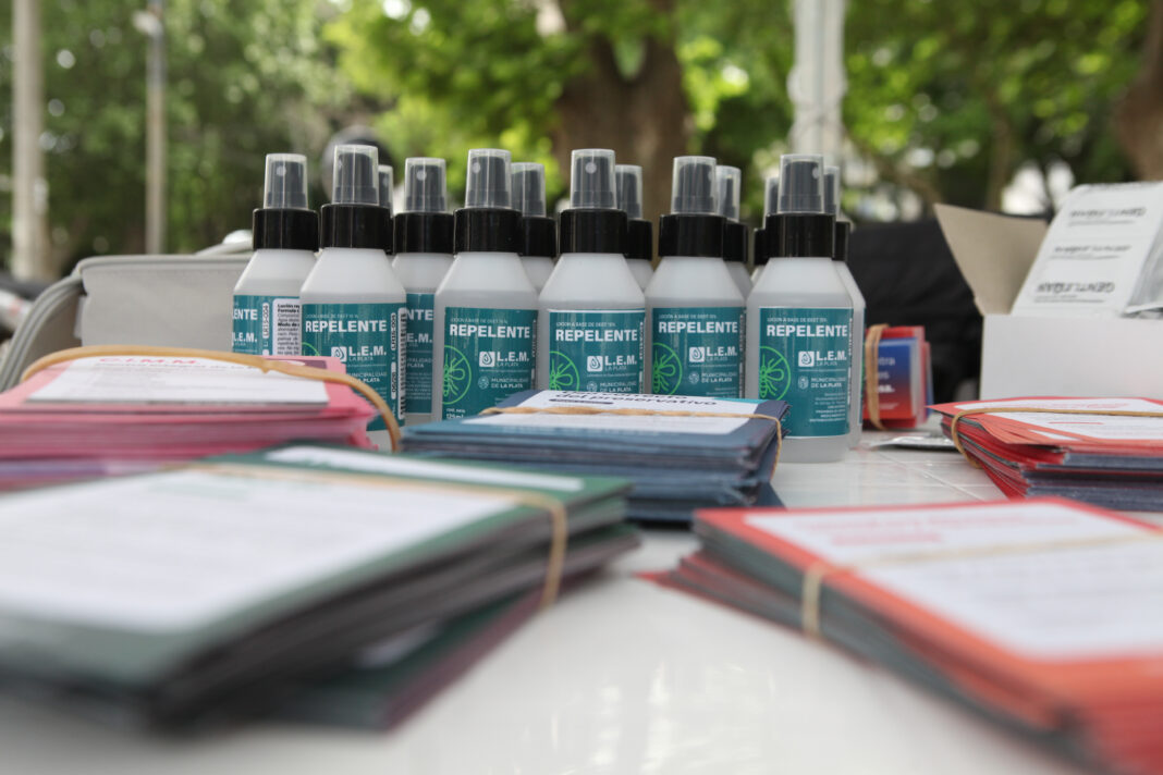 Repelente Municipal en La Plata: Acciones Contra el Dengue Botellas de repelente de insectos provistas por el Municipio de La Plata durante jornadas preventivas contra el dengue en plazas y jardines.