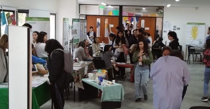 Personas recorren stands y pósters científicos en una feria organizada por el IdIHCS, en defensa de la ciencia argentina.