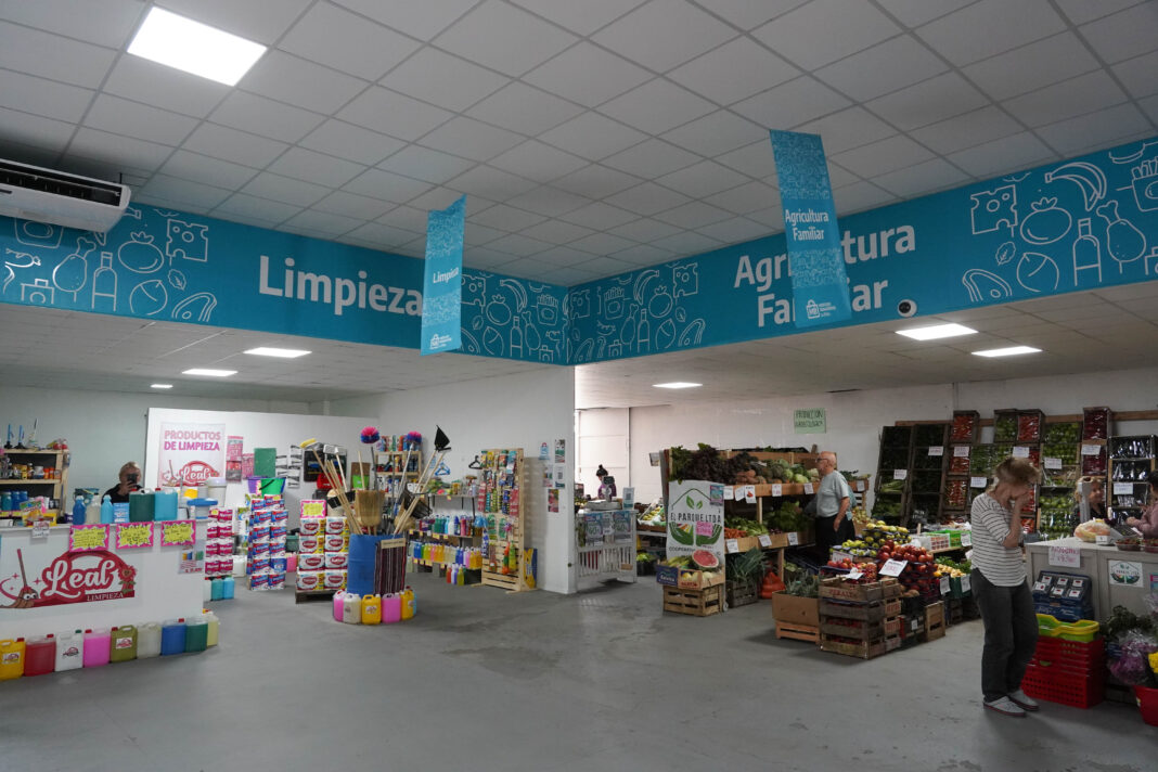 Interior del Mercado Bonaerense Fijo en La Plata mostrando secciones de limpieza y agricultura familiar con ofertas disponibles