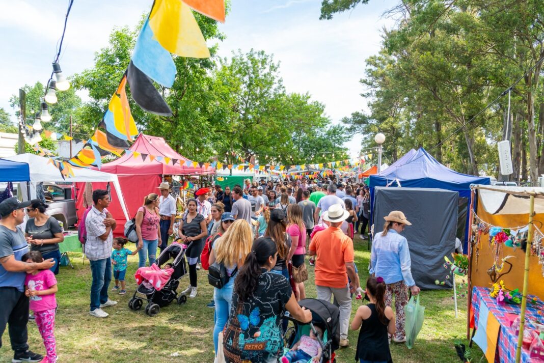 Feria al aire libre con puestos, banderines y familias recorriendo actividades en la Provincia de Buenos Aires durante el fin de semana largo.