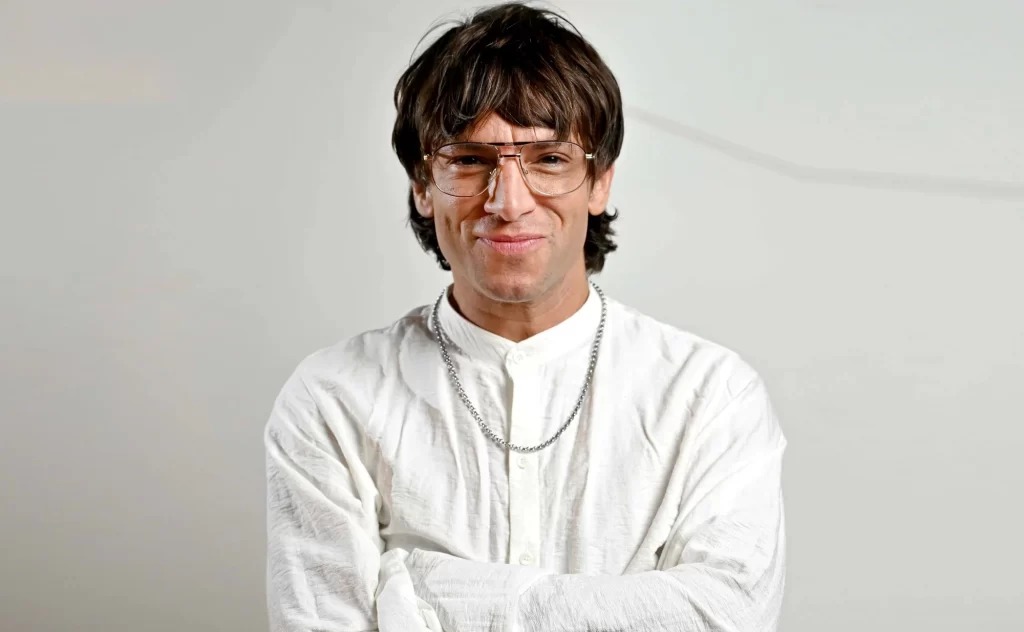 Primer plano de Joaquín Levinton con camisa blanca y gafas de aviador, en una foto de estudio para ilustrar la noticia de su infarto y urgencia.