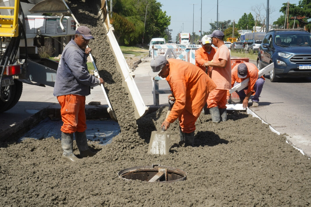 Equipo de obreros vertiendo y nivelando hormigón fresco de un camión mezclador sobre una sección de la Avenida 44 en La Plata, como parte de las obras de mejora del acceso vial.