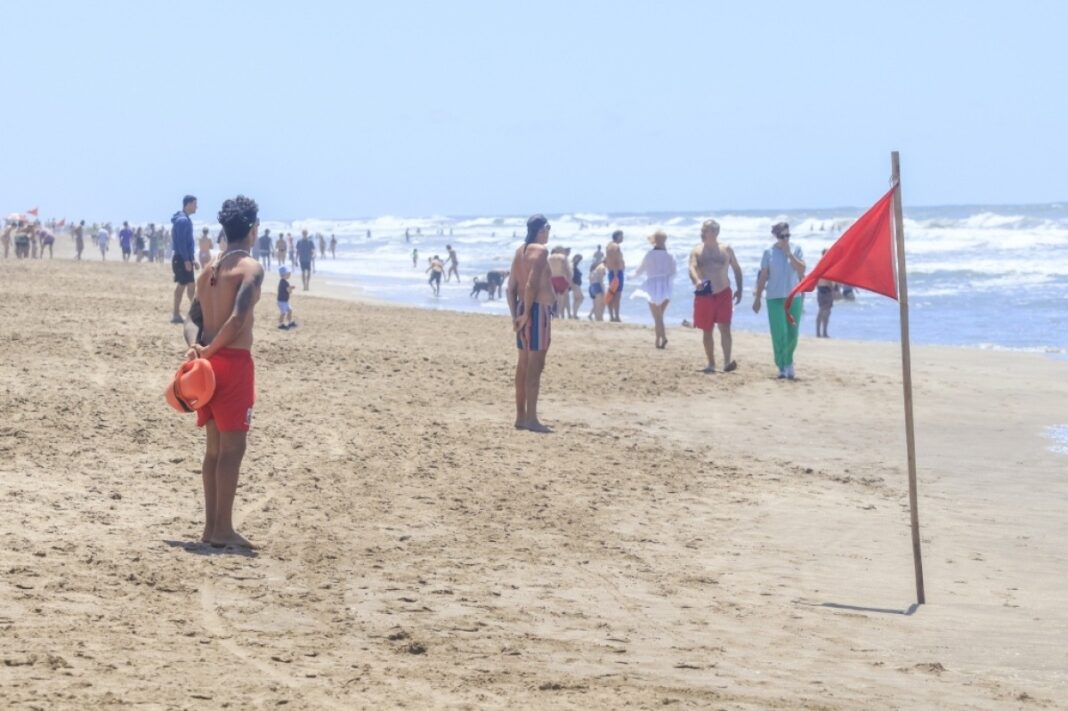 Guardavidas observando el mar en una playa de Villa Gesell con bandera roja, alertando sobre el peligro de las corrientes de resaca.