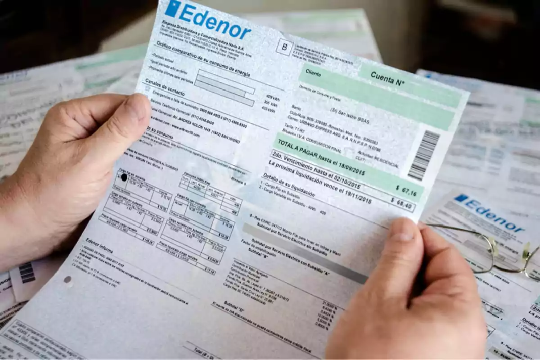 Persona sosteniendo una boleta de Edenor junto a otras facturas, en el marco de los aumentos de tarifas y el nuevo esquema de subsidios energéticos desde enero de 2026.