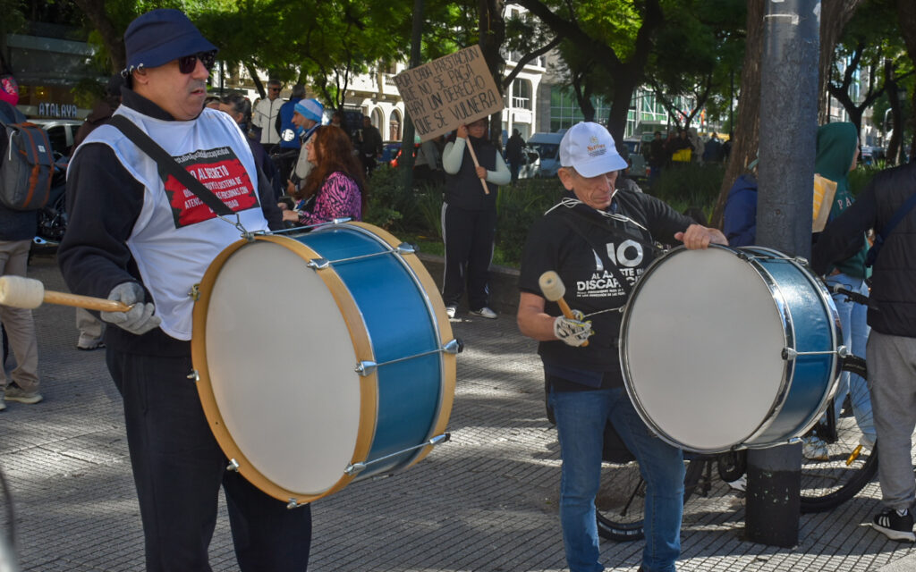 dos hombres tocan el bombo en una marcha por los derechos de las personas con discapacidad afuera del ministerio de salud de la nacion