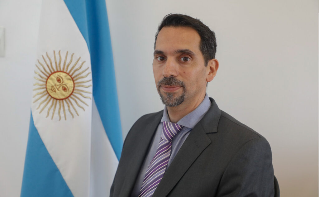 martin porro posa delante de una bandera argentina